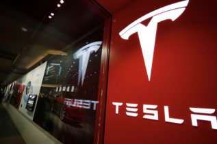 Obrazek przedstawia logo firmy Tesla, czyli producenta auta elektrycznego, o którym jest artykuł.